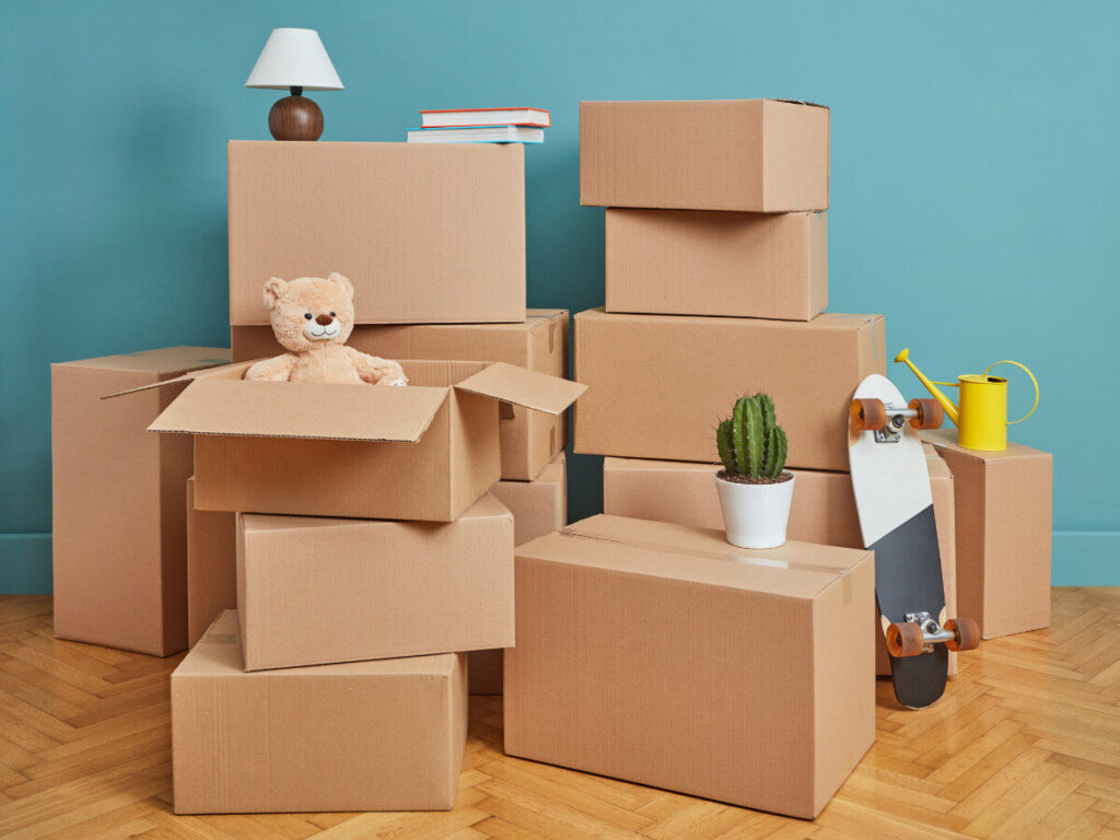 部屋に積まれた引っ越し用の段ボールとぬいぐるみ