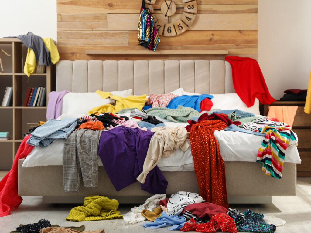 ベッドの上に衣類が散乱した汚部屋の寝室の様子