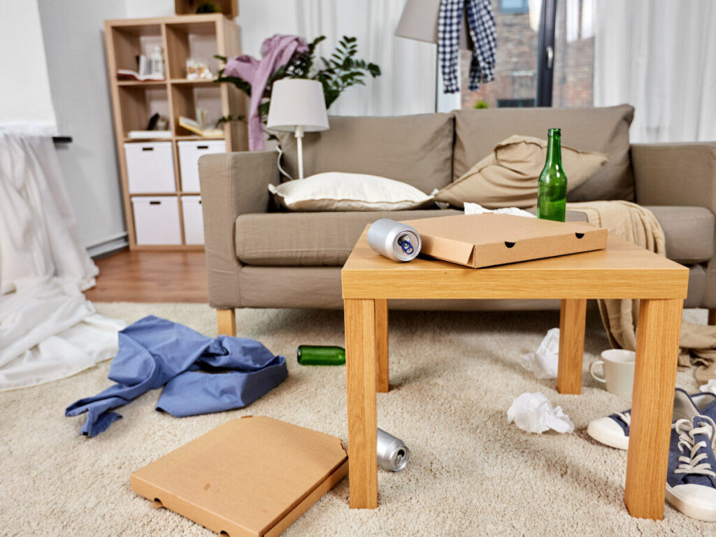 空き缶やピザの箱が散乱したリビングルームのテーブルまわり