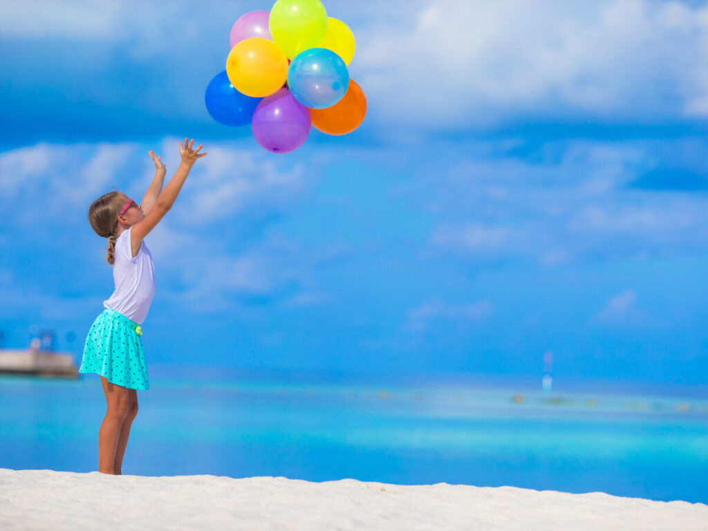 カラフルな風船を空に放つ女の子